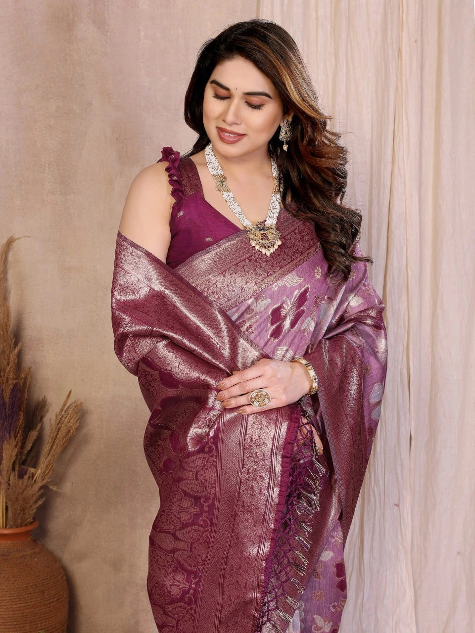 Woman wearing a purple saree with a matching blouse against a beige background